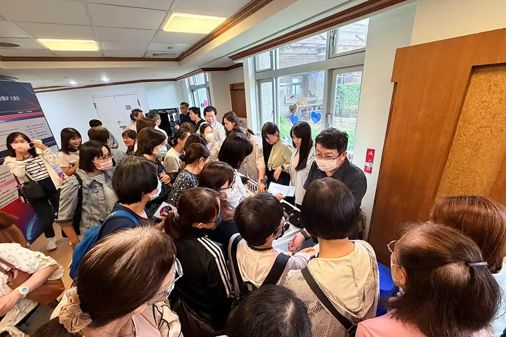 現場醫療專業人員圍繞展示桌，體驗脈安扣裝置操作方式